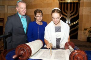 נערה עם הוריה בטקס בת מצווה בבית כנסת.